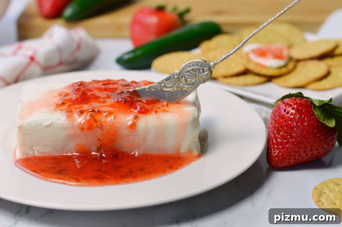 Spicy Jalapeño Strawberry Jam Recipe 7 block of cream cheese with spreader and jalapeno jelly poured over it.