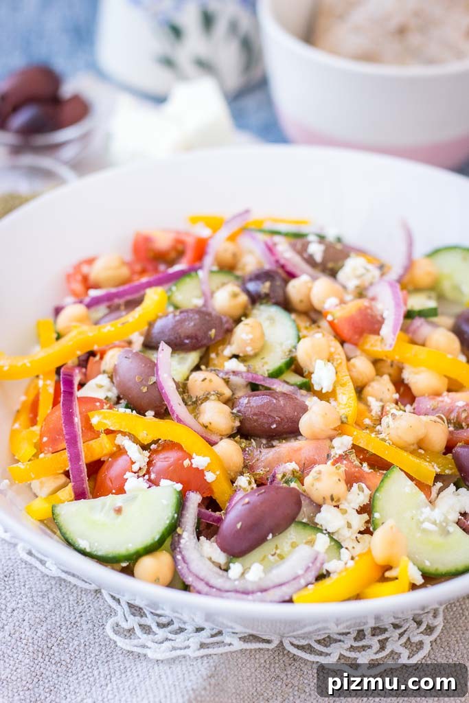 Greek Chickpea Salad with tomatoes, cucumber, olives, feta, and Greek Salad Dressing served in a bowl