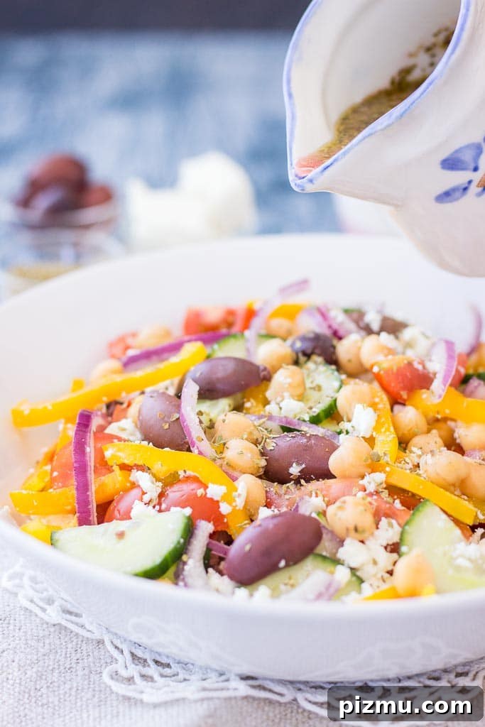 Greek style chickpea salad with tomatoes, cucumber, olives, feta, and Greek Salad Dressing served in a bowl
