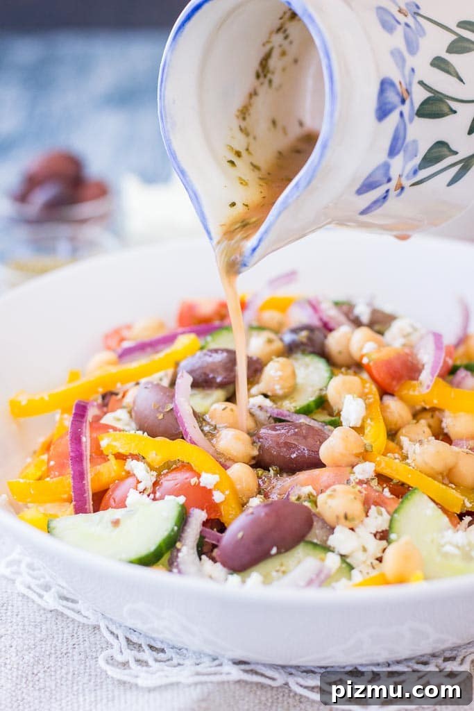 Greek style chickpea salad with tomatoes, cucumber, olives, feta, and Greek Salad Dressing served in a bowl