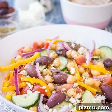 Greek Chickpea Salad with tomatoes, cucumber, olives, feta, and Greek Salad Dressing served in a bowl