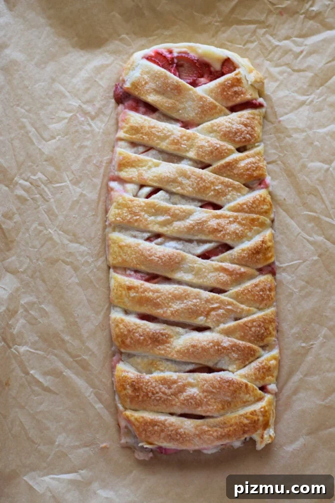 Homemade Strawberry Puff Pastry Danish Recipe 11 Baked strawberry cream cheese pastry braid on a baking tray.