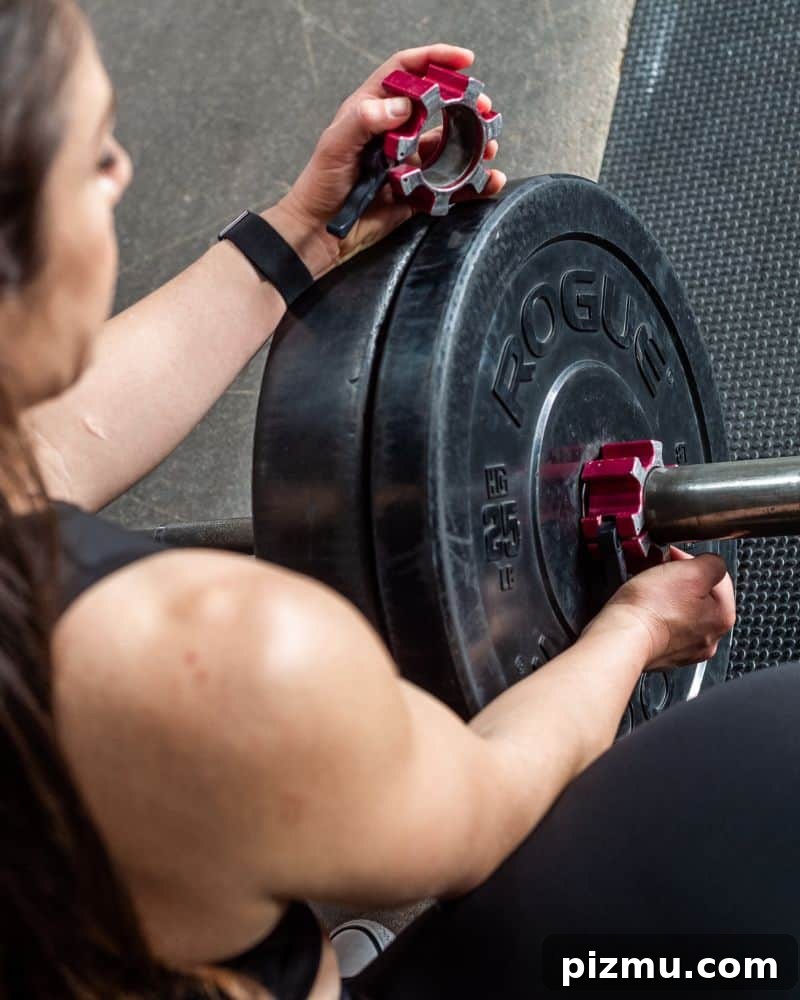 Within-Day Energy Deficit: What It Is and Why It Matters 4 woman adds clamp to end of barbell