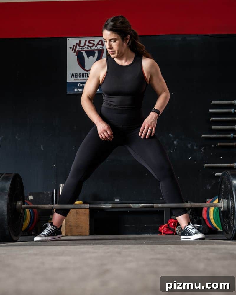 Within-Day Energy Deficit: What It Is and Why It Matters 6 woman stands in a gym preparing to do a deadlift