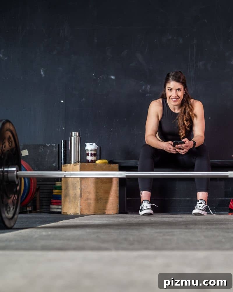 Within-Day Energy Deficit: What It Is and Why It Matters 2 woman sits on a bench in the gym with a barbell on the floor in front of her