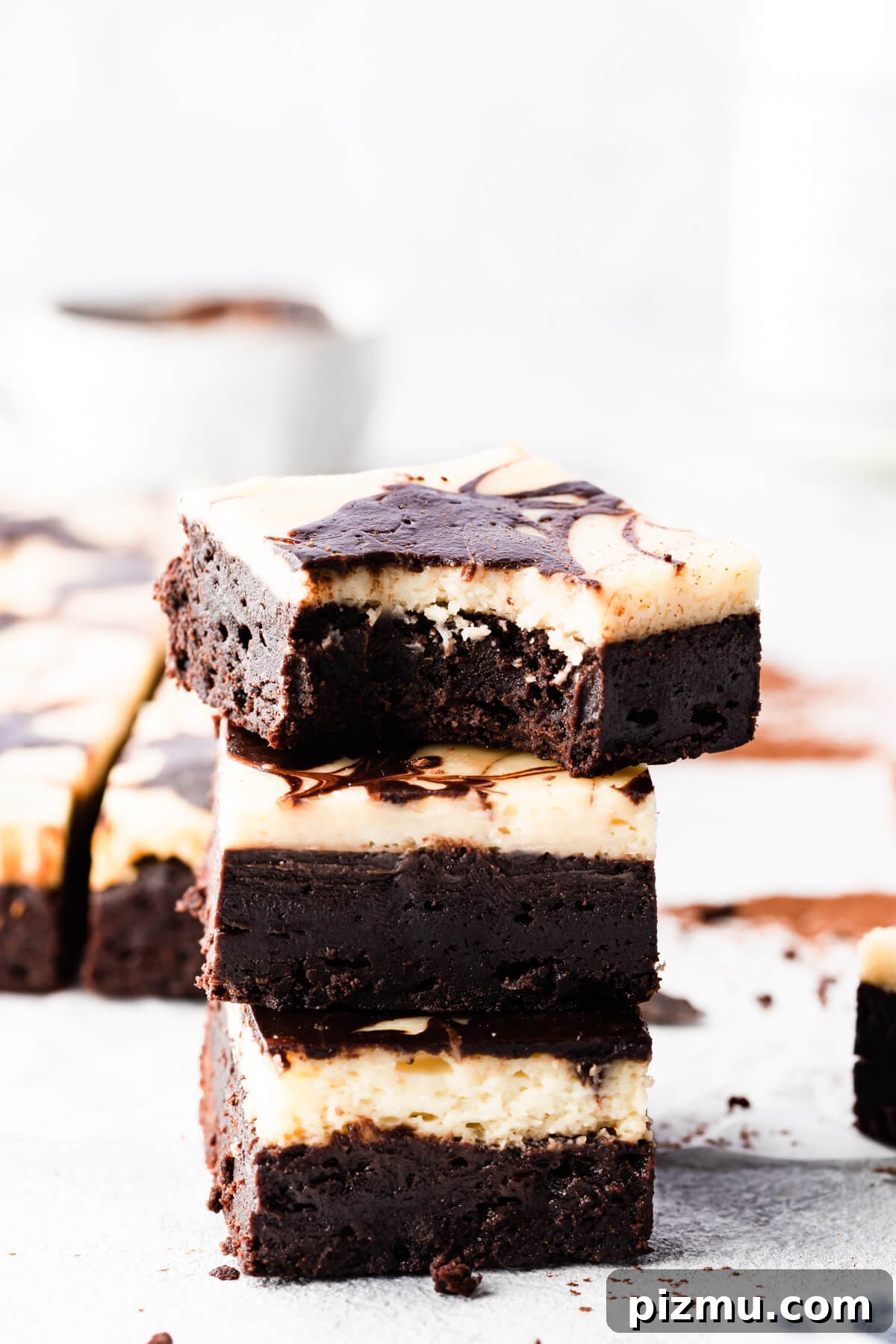 Cheesecake Swirl Brownies with Cream Cheese Filling 3 side close up of stack of brownies with the top one missing a bite