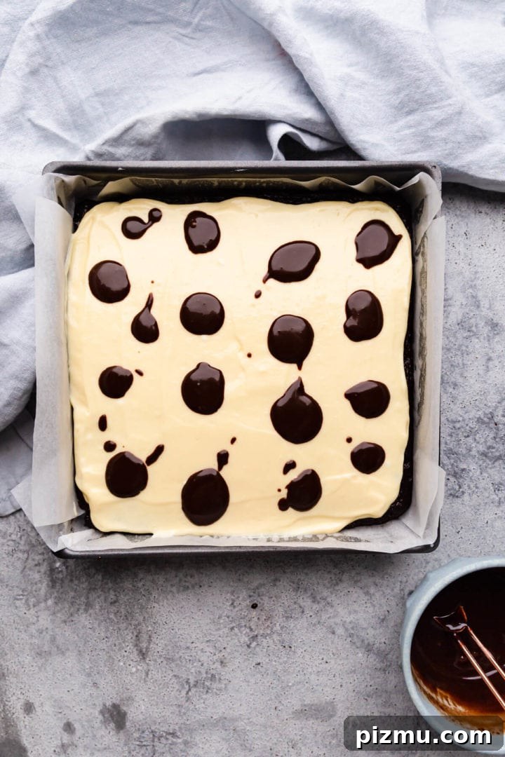 Cheesecake Swirl Brownies with Cream Cheese Filling 8 top view of the baking tin with cake batter and dollops of chocolate on top