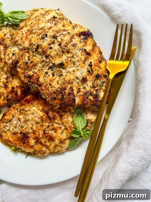Juicy Grilled Lemon Chicken with Garlic and Herbs 8 Grilled seasoned chicken breasts on a plate garnished with basil.