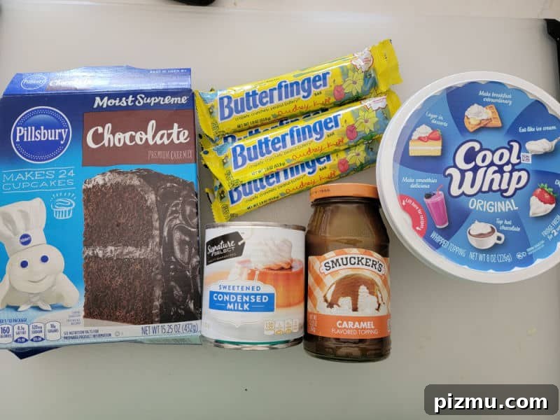 Butterfinger Cake Recipe with Chocolate Peanut Butter Crunch 3 Butterfinger poke cake ingredients, chocolate cake mix, Butterfinger candy bars, cool whip, sweetened condensed milk, and caramel topping on a white counter