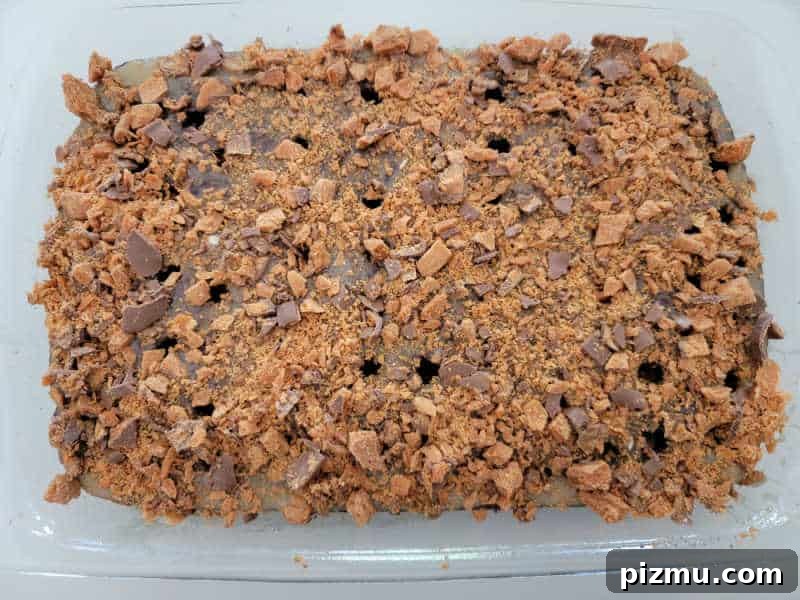 Butterfinger Cake Recipe with Chocolate Peanut Butter Crunch 6 Crushed Butterfinger candy over a poke cake