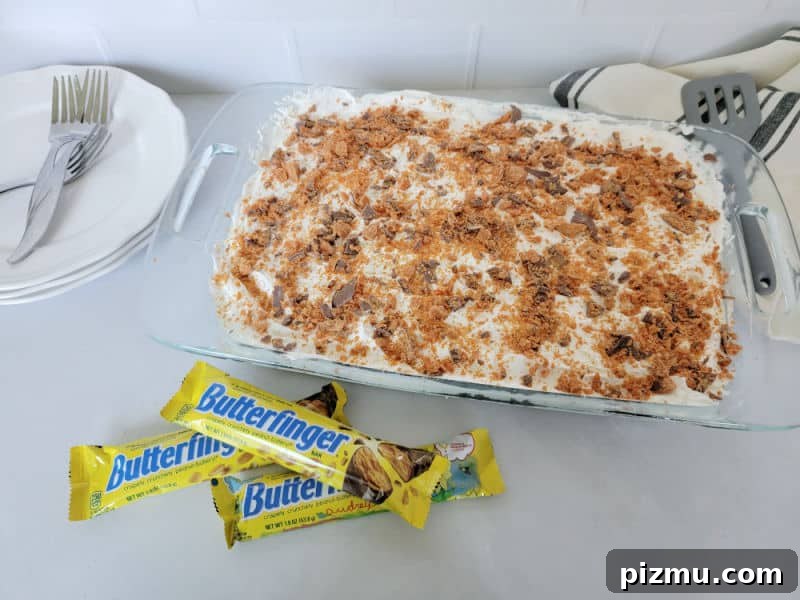 Butterfinger Cake Recipe with Chocolate Peanut Butter Crunch 9 Butterfinger cake in a large dish next to Butterfinger candy bars