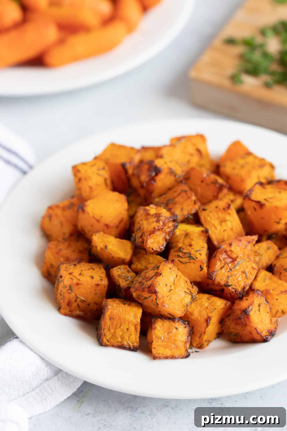 Crispy Air Fryer Butternut Squash with Garlic and Herbs 6 Air fried butternut squash cubes on a plate.