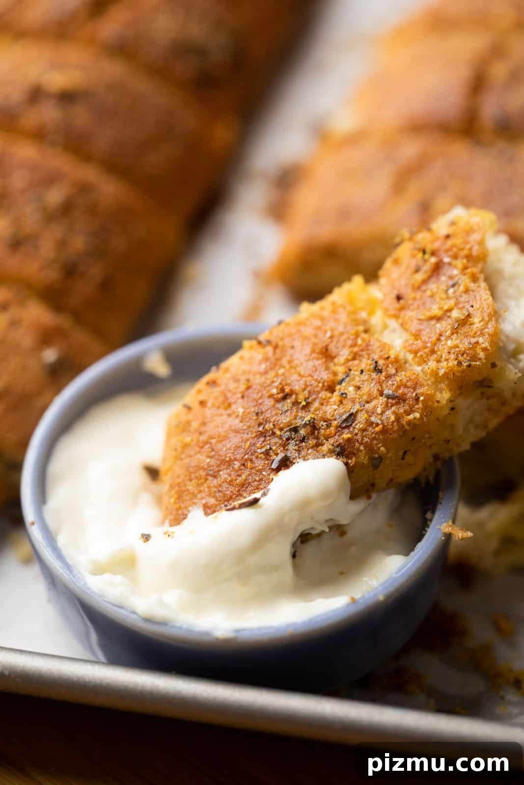 Domino-Style Garlic Breadsticks: Two Ways 4 Closeup of a breadstick dipped in cheese sauce