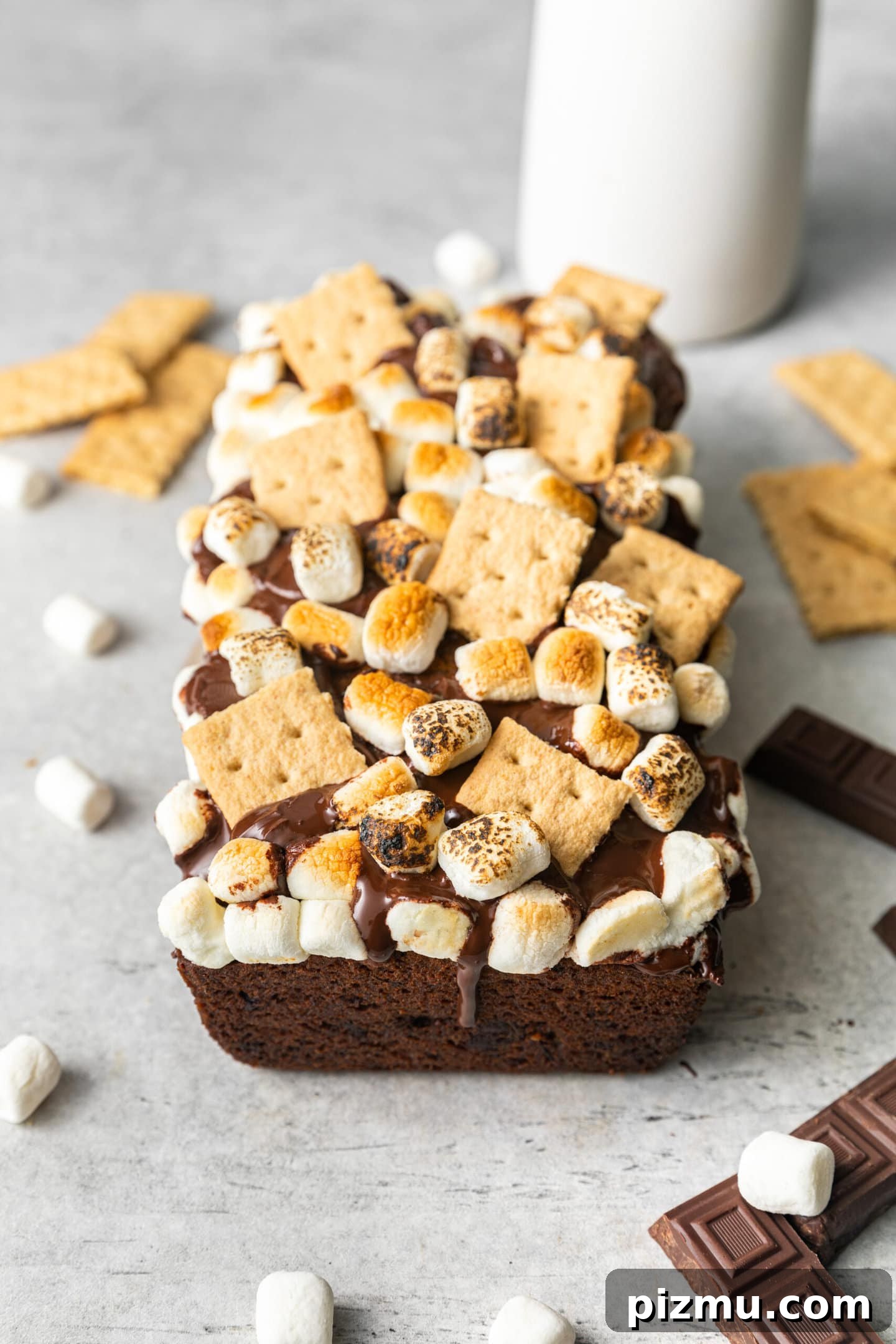 S'mores Banana Bread surrounded by mini marshmallows, graham crackers, and chocolate squares.