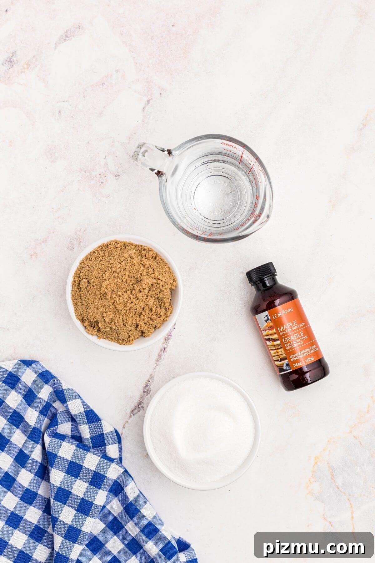 Sugar, brown sugar, water, and maple extract on a marble table.