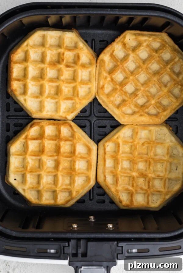 Fully cooked frozen waffles in air fryer basket in a single layer.