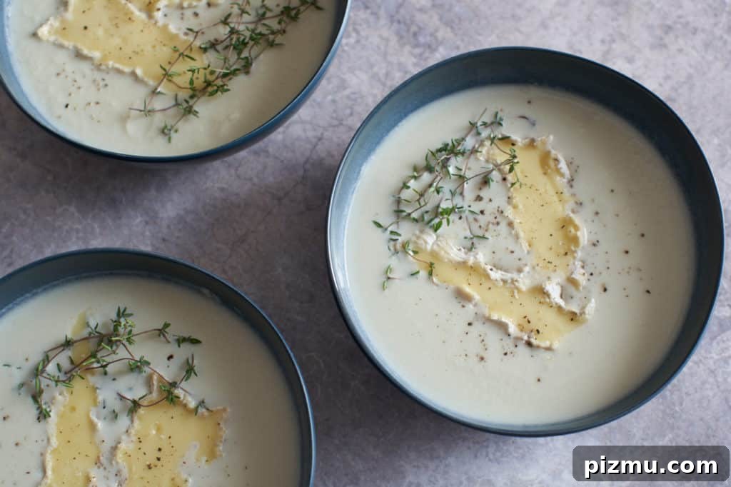 Creamy French Cauliflower Soup with Brie 2 Three bowls of creamy cauliflower soup with brie on top.