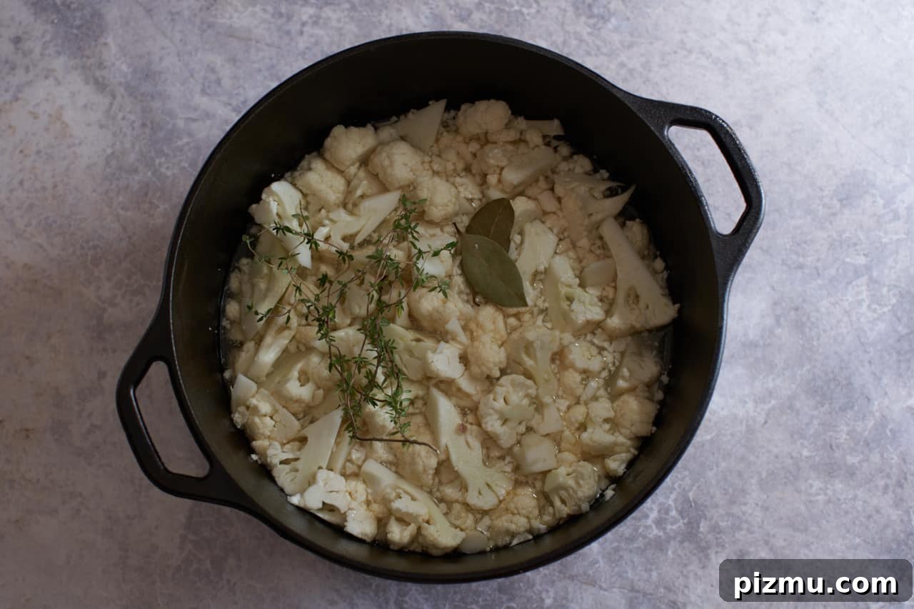Creamy French Cauliflower Soup with Brie 5 Chopped cauliflower in a pot with bay leaves and thyme.
