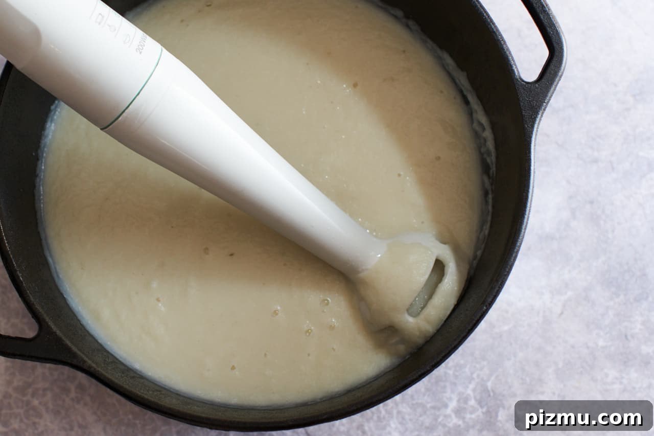 Creamy French Cauliflower Soup with Brie 6 Creamy cauliflower soup being blended in a pot.