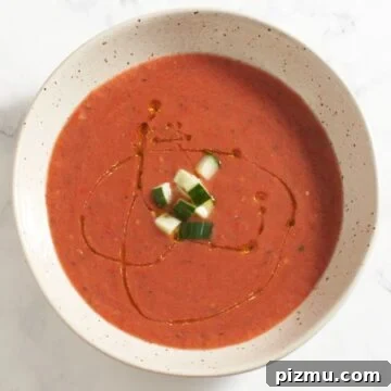 Top down view of a bowl of gazpacho topped with chopped cucumber