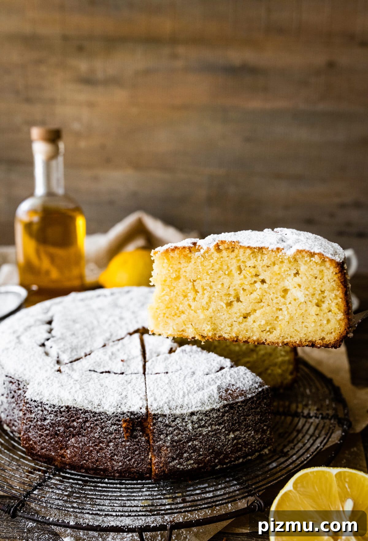 baked best olive oil cake with powdered sugar on top. Cake cut into slices. One slice is taken out with a cake server. 
