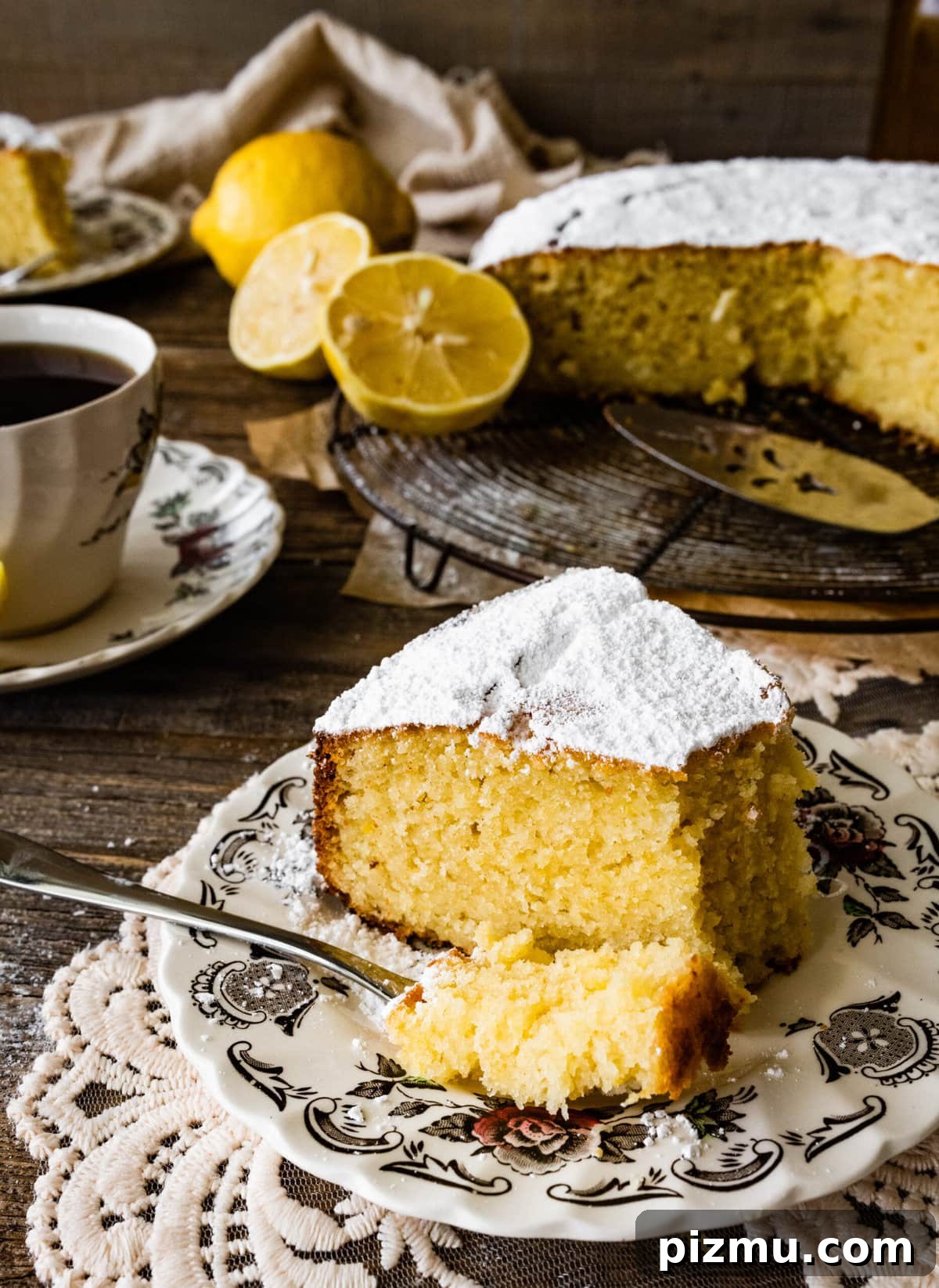 side photo of thick slice on a plate of the best olive oil cake recipe. Bite taken out with a fork.
