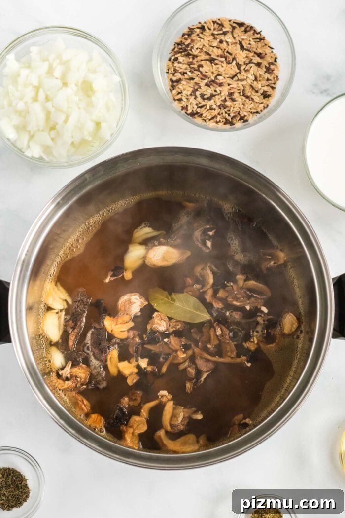 Creamy Vegan Mushroom and Wild Rice Soup 4 Vegetable broth in a pot with chopped wild mushrooms and a bay leaf.