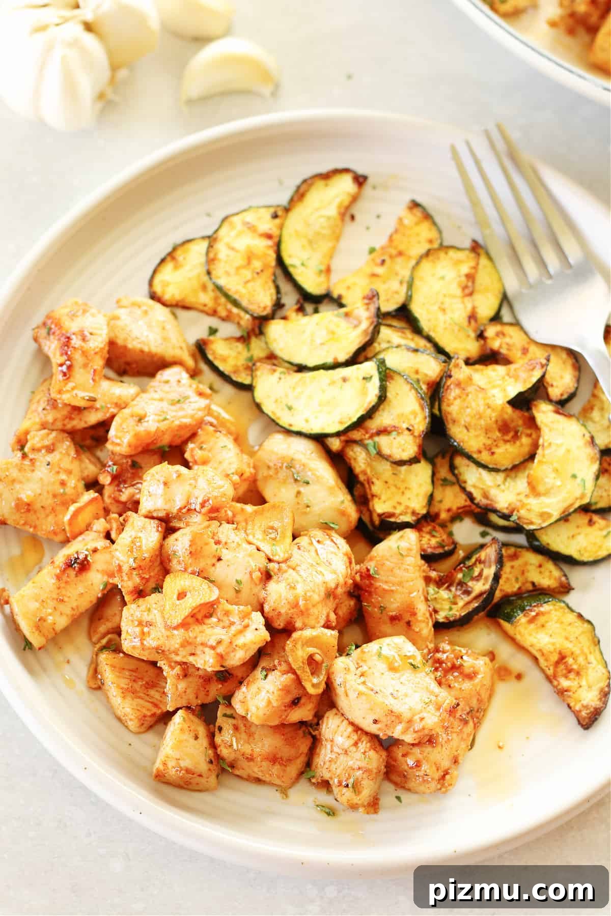 Chicken Bites with Garlic Butter Sauce. Chicken bites and cooked zucchini slices on a dinner plate.