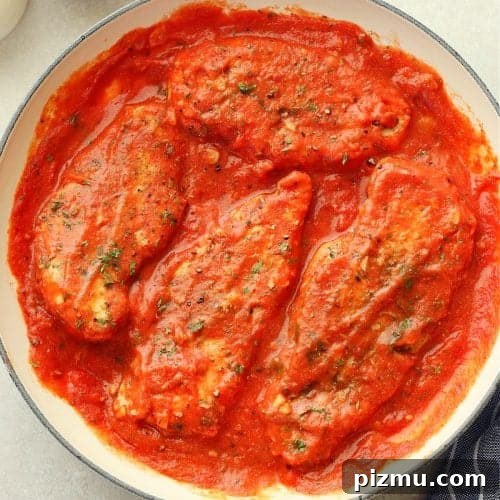 Chicken breasts in a creamy tomato sauce in a skillet.