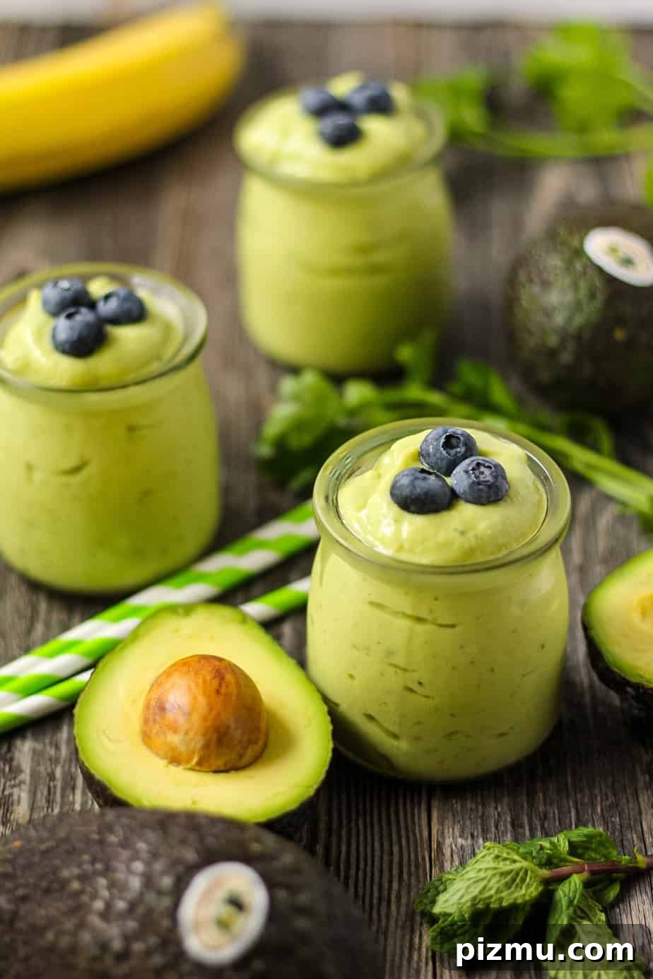 Creamy Tropical Avocado Smoothie Recipe 2 side shot of tropical avocado smoothies with fresh avocados in perimeter of shot