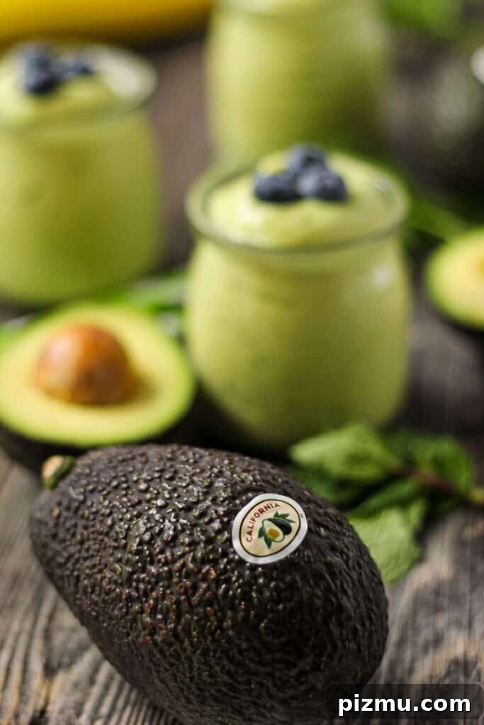 Creamy Tropical Avocado Smoothie Recipe 4 avocado smoothies in clear glasses on wood surface with a whole avocado in front of shot