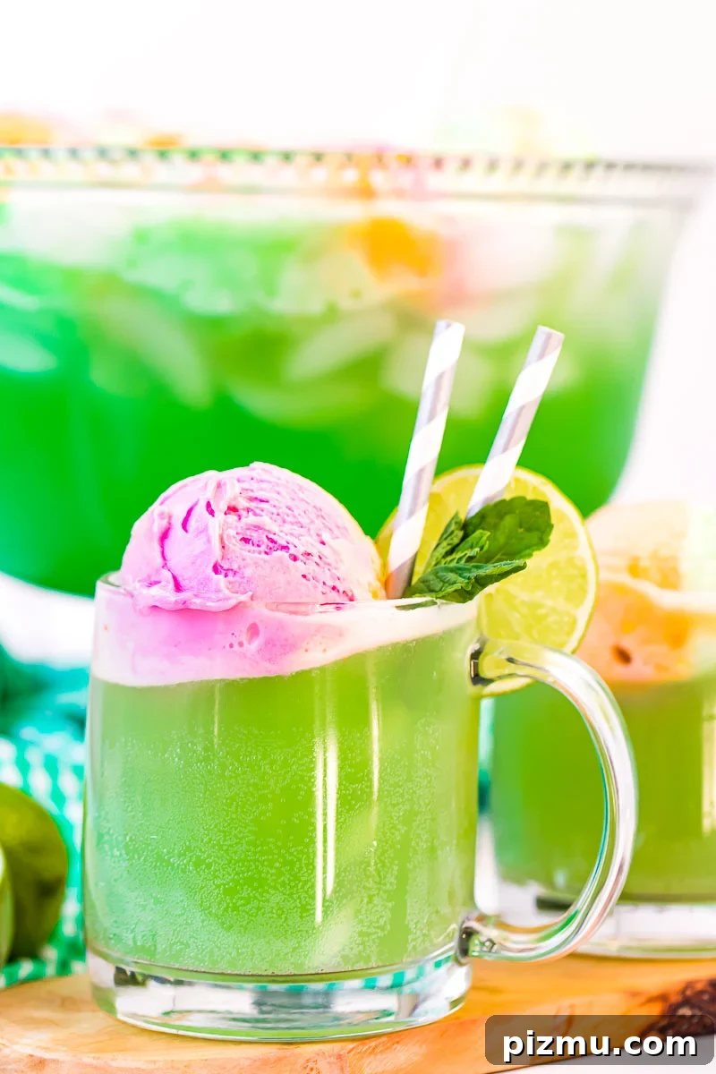 Close up photo of a clear mug filling with green punch.