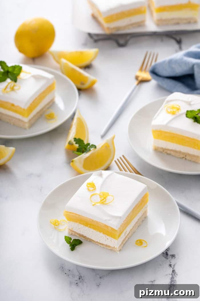 Creamy Layered Lemon Trifle Recipe 3 Three white plates, each holding a slice of layered lemon dessert with more dessert in the background.