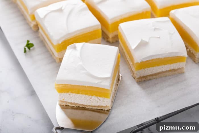 Creamy Layered Lemon Trifle Recipe 4 Slices of layered lemon dessert on a piece of parchment paper.