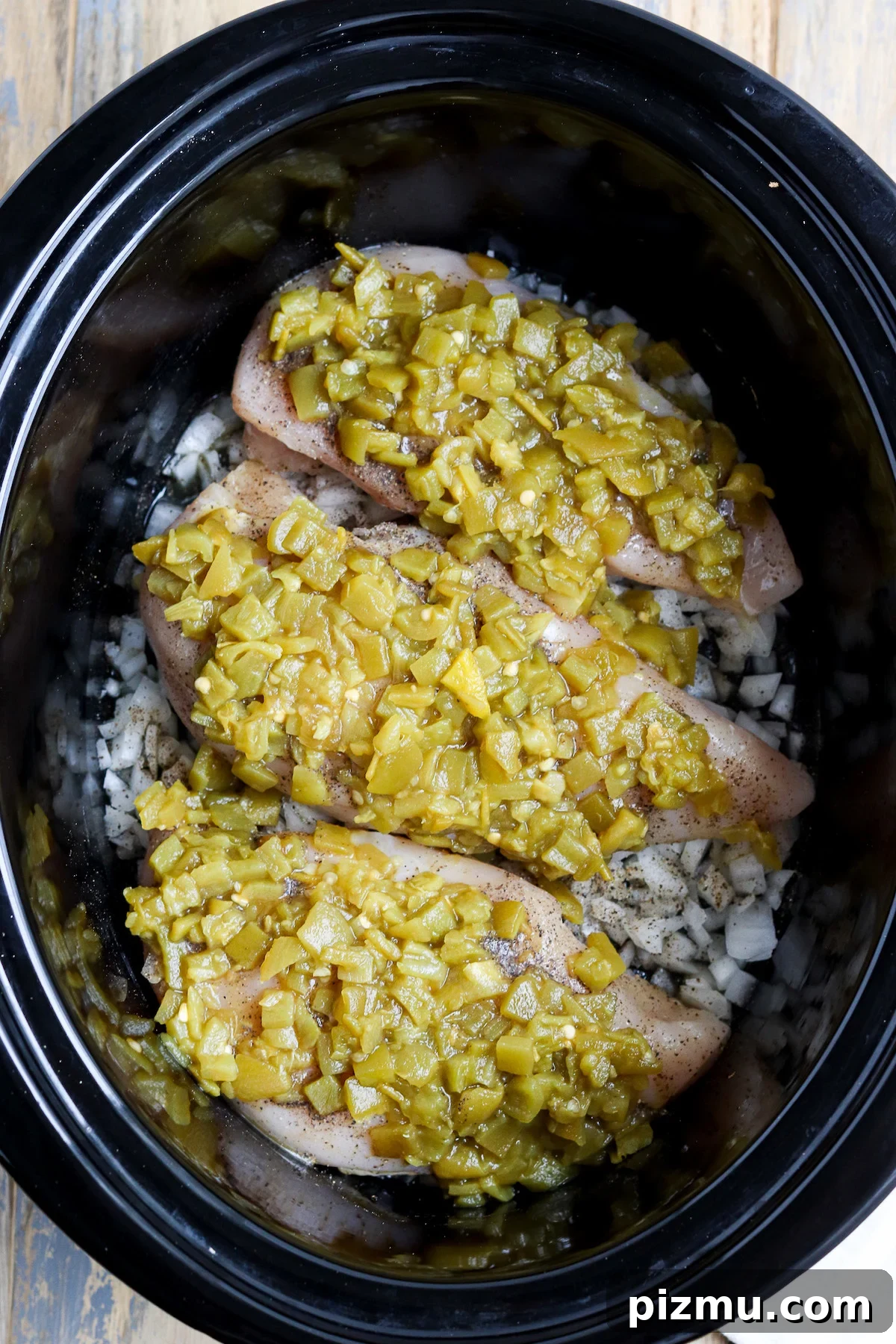 Slow Cooker Green Chile Chicken Recipe 3 crockpot layered with onions, chicken breast and green chiles before cooking