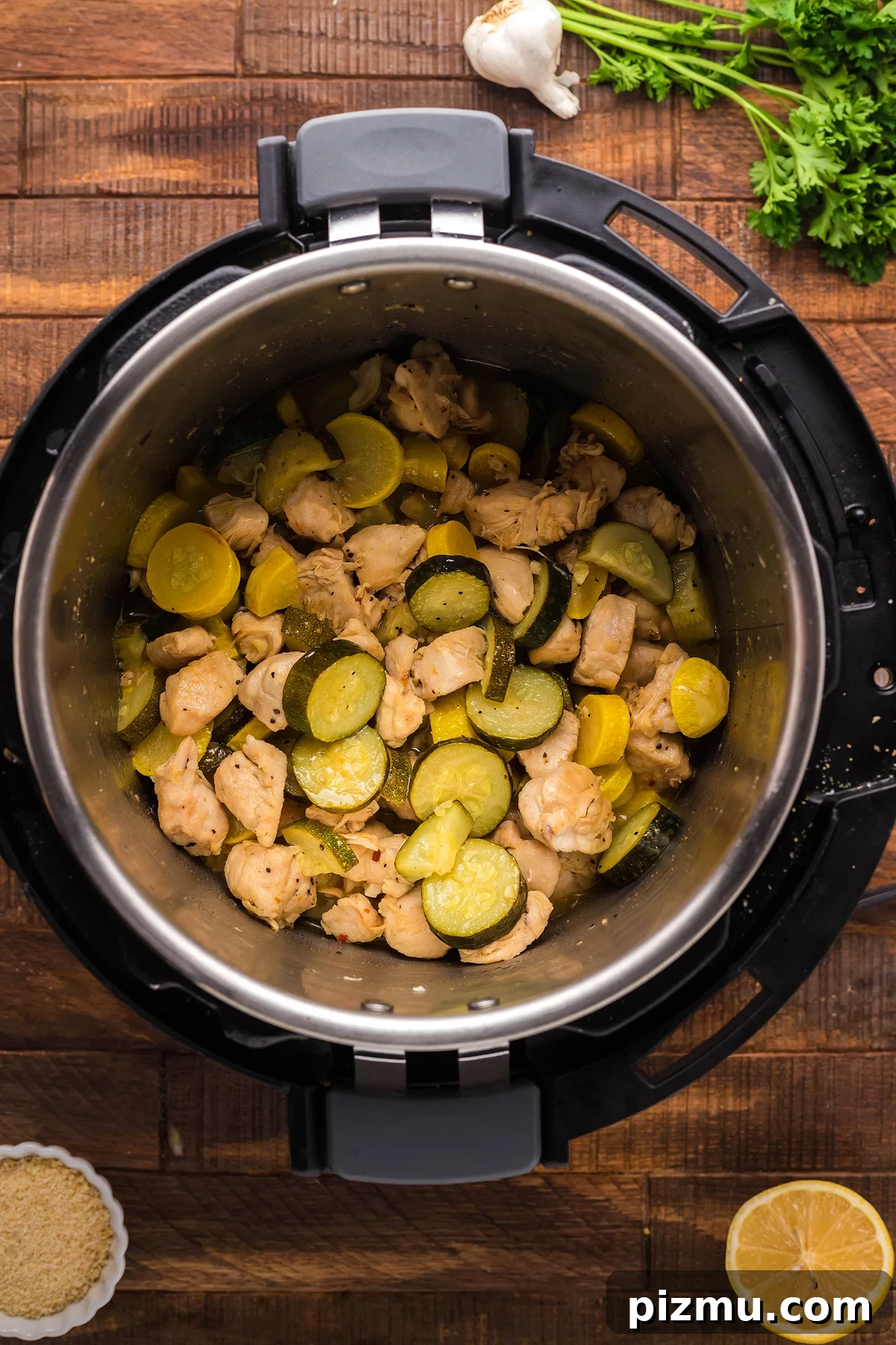 Creamy Lemon Chicken Pasta in the Instant Pot 17 Chicken, zucchini, and yellow squash cooked in an Instant Pot on a wooden table with herbs and garlic nearby—perfect for making pasta with chicken and vegetables.
