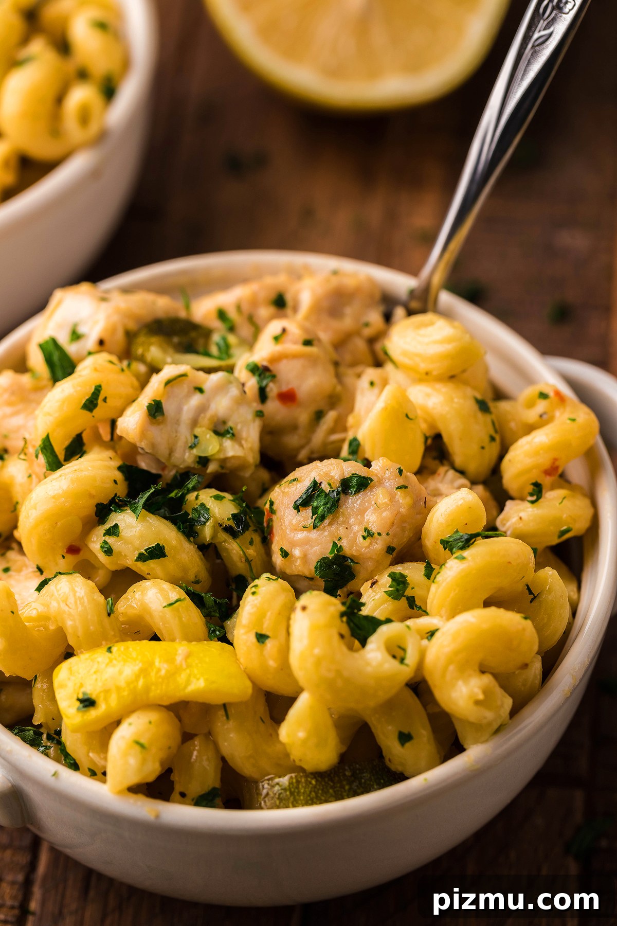 Creamy Lemon Chicken Pasta in the Instant Pot 3 A bowl of curly pasta with chicken, yellow bell peppers, and fresh herbs, featuring a fork inside—perfect for an easy instant pot pasta dinner or when you crave pasta with chicken and vegetables.