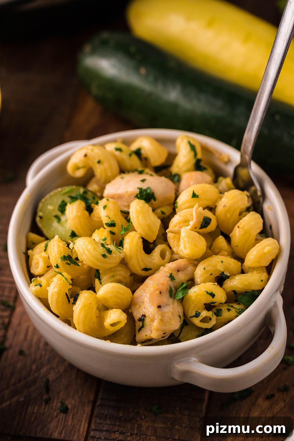 Creamy Lemon Chicken Pasta in the Instant Pot 4 A bowl of Pasta with Zucchini and Squash and tender chicken, garnished with chopped herbs, sits on a wooden table—perfect for fans of Instant Pot Lemon Chicken Pasta.
