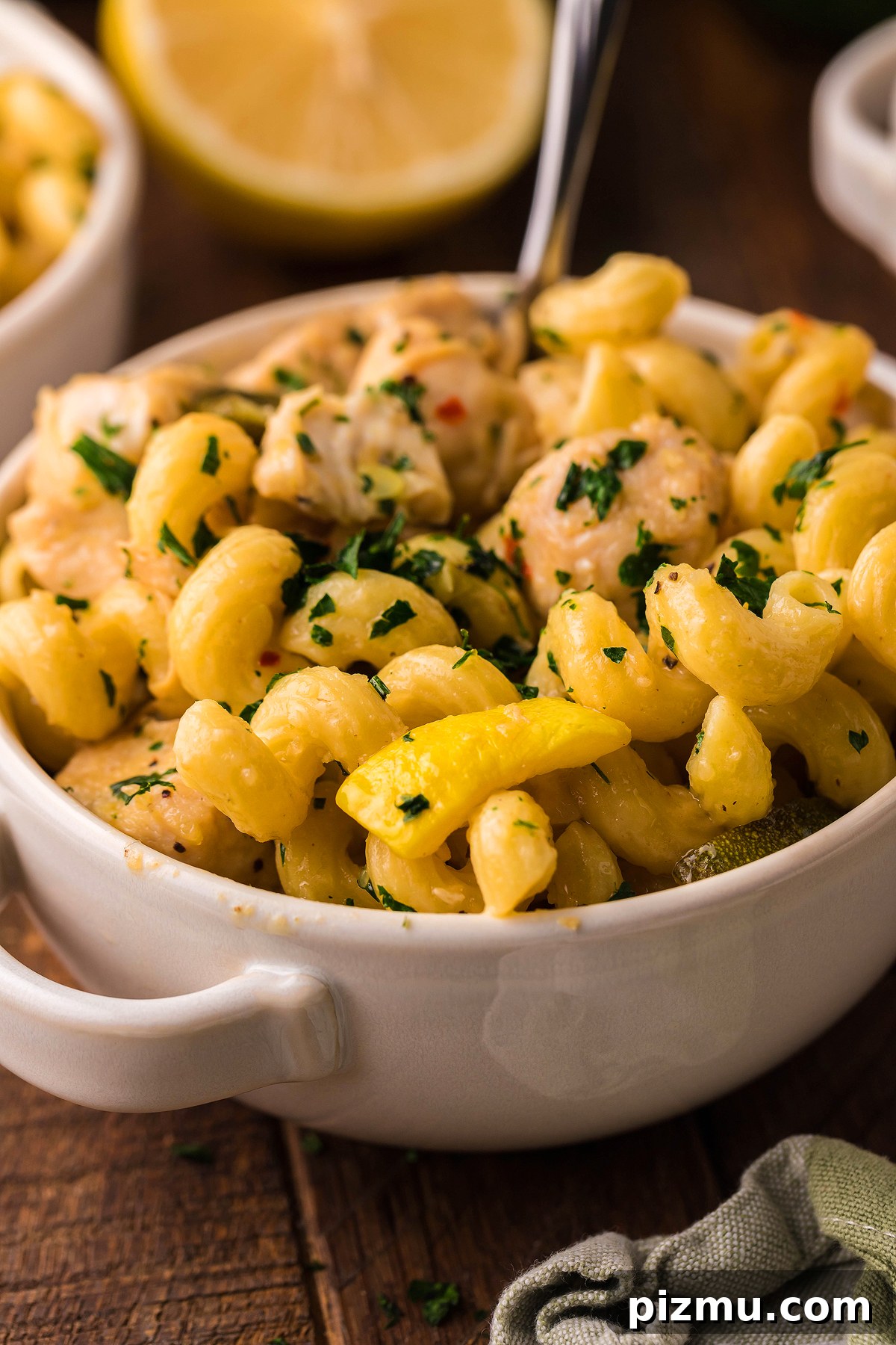 Creamy Lemon Chicken Pasta in the Instant Pot 6 Curly pasta with creamy sauce, chicken, and parsley in a white bowl, with lemon in the background—perfect for Instant Pot Lemon Chicken Pasta lovers.