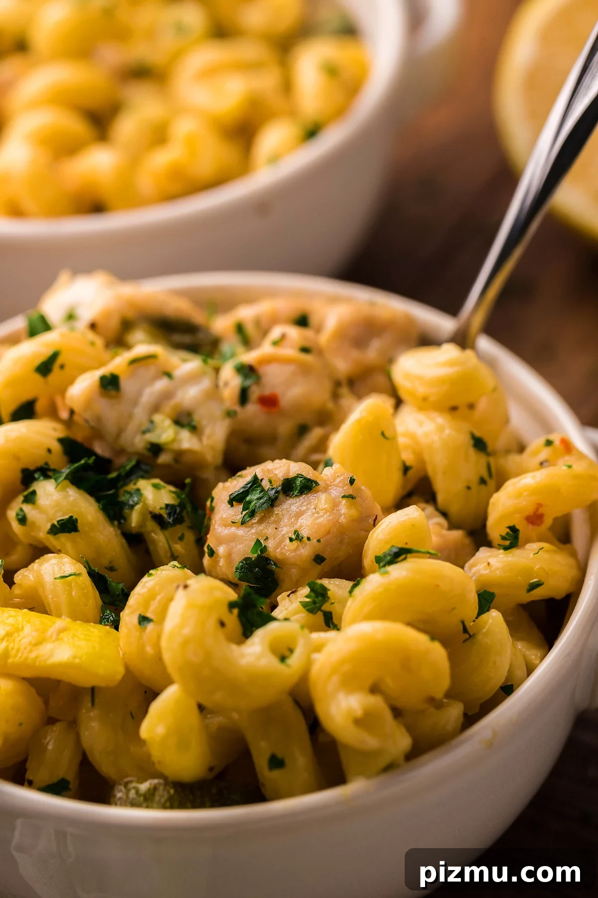 Creamy Lemon Chicken Pasta in the Instant Pot 7 Creamy Instant Pot Lemon Chicken Pasta with tender chicken pieces, garnished with chopped parsley, served in a white bowl.