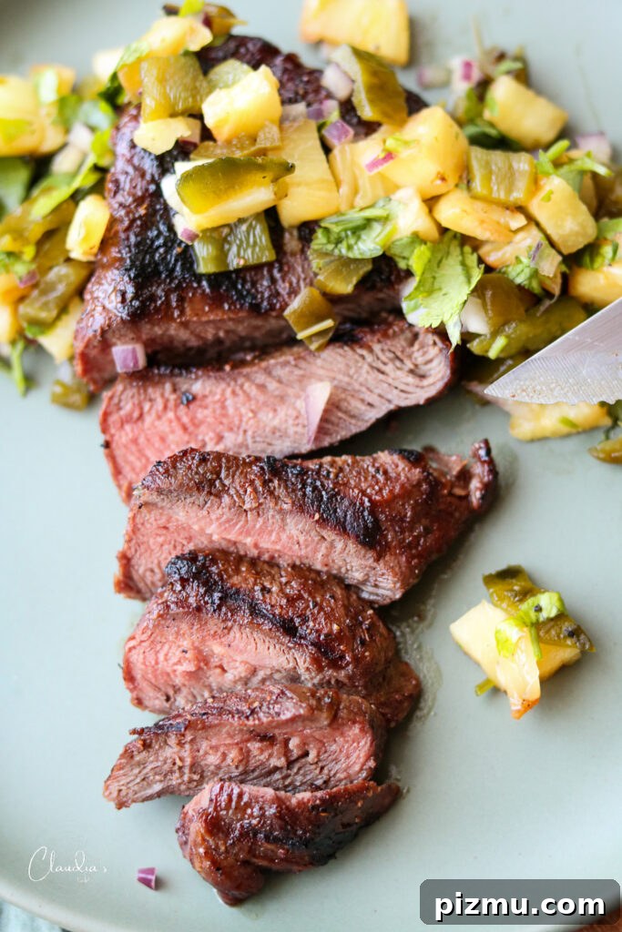 Grilled Steak with Charred Pineapple Jalapeno Salsa 14 ancho Chile rubbed steak with grilled pineapple salsa on green plate with knife