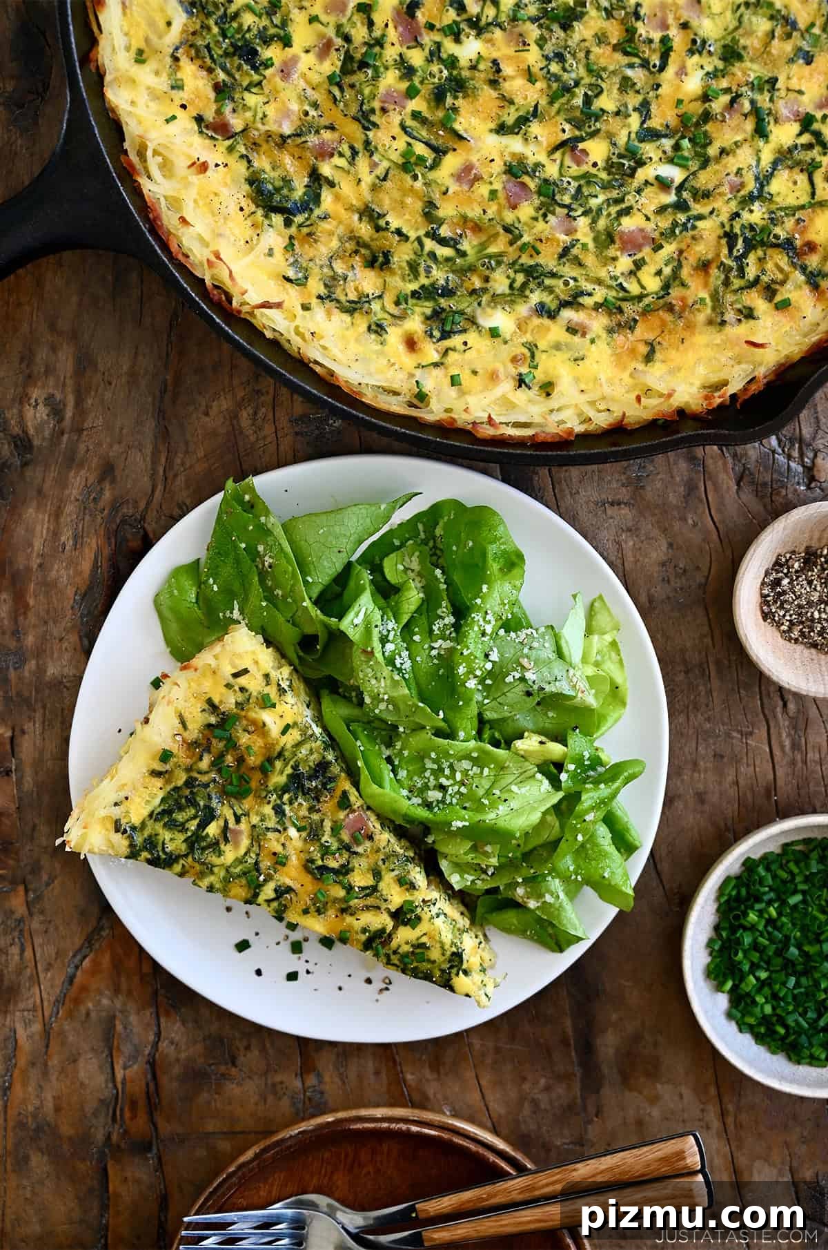 Ham and Cheese Quiche with Crispy Hash Brown Crust 11 A slice of ham and cheese quiche with a crispy hash brown crust on a plate with dressed greens.