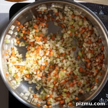 Classic Italian Lentils with Garlic and Rosemary 4 Carrots, onion, and celery sauteing in a saucepan.