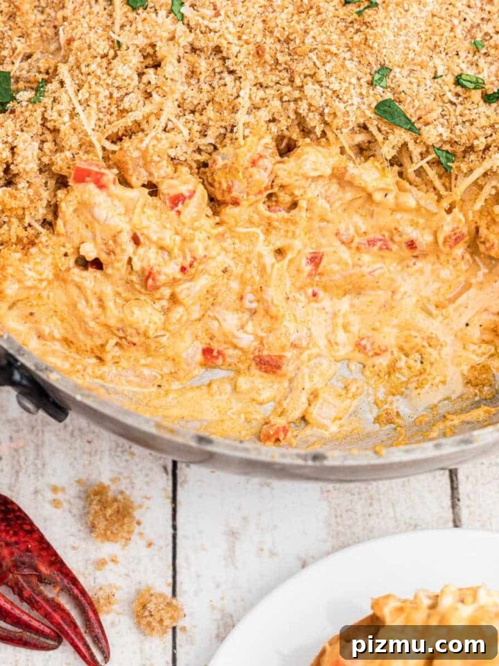 skillet of crawfish dip with breadcrumbs on top, with cream cheese. Crawfish in the corners.