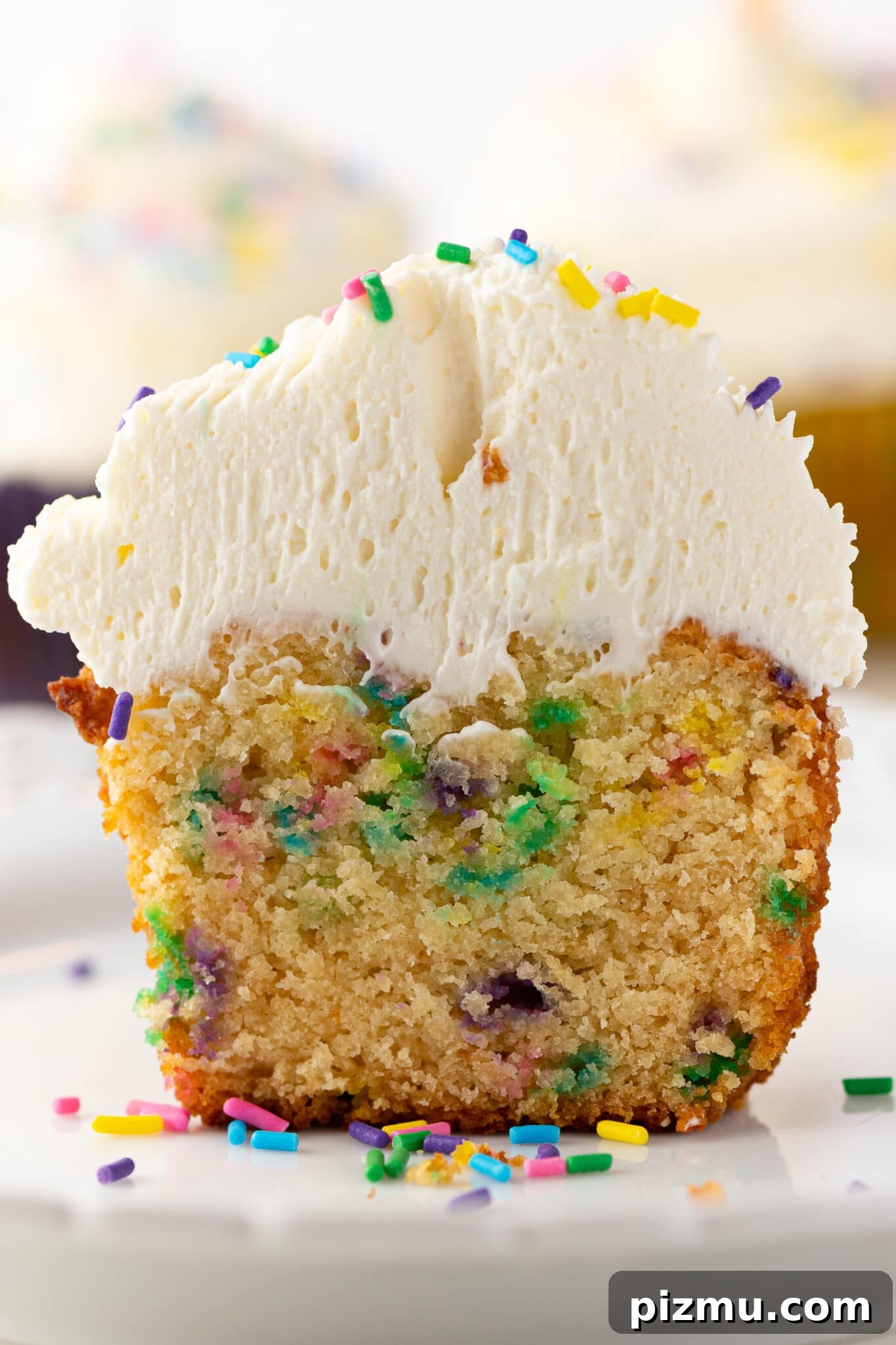 11 Keto Muffins for Quick Grab-and-Go Mornings 10 Low-carb cupcakes with sprinkles and frosting piled high. The muffin is split in half to show the texture inside. The image intended to show an example of keto muffin recipes you can make on a carb restricted diet.
