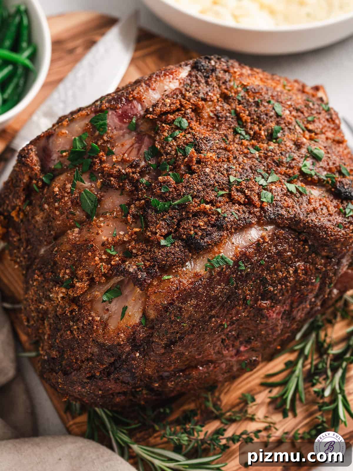 Bone-In Prime Rib Roast 2 Overhead view of a roasted prime rib, sprinkled with fresh herbs.