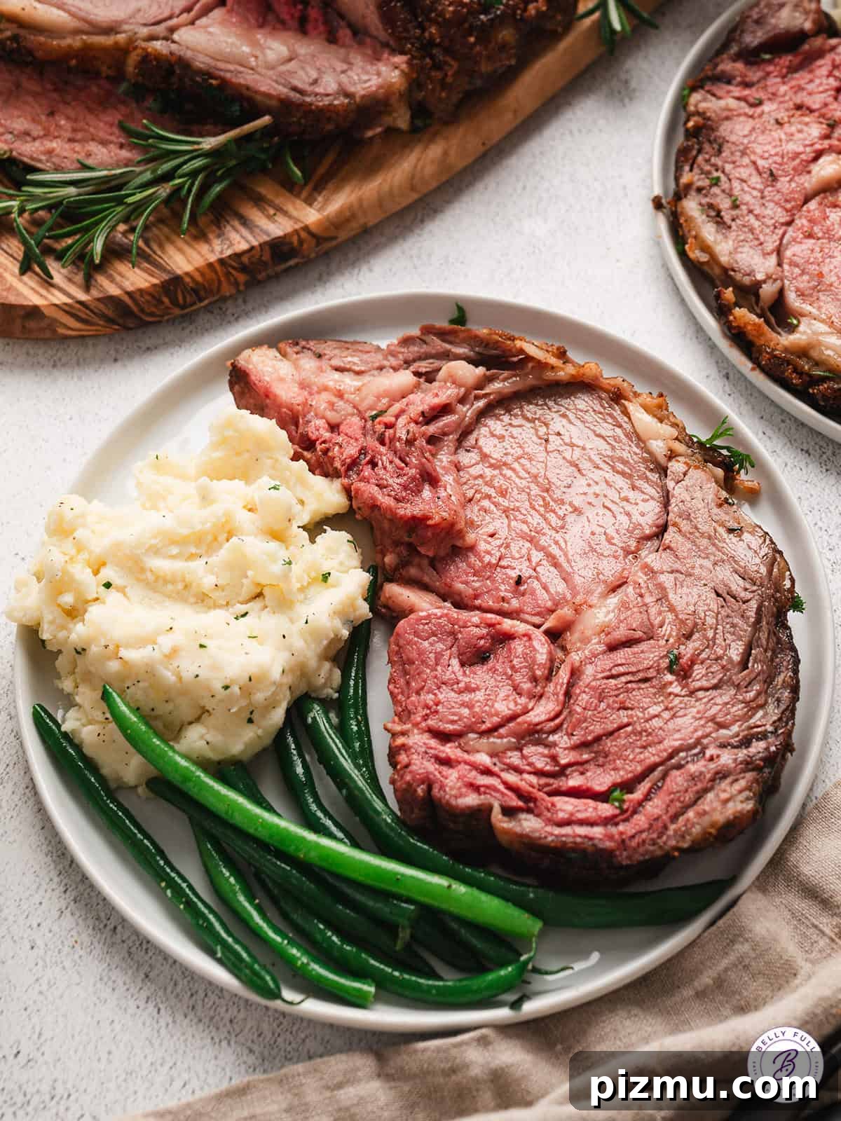 Bone-In Prime Rib Roast 4 A slice of prime rib roast on a plate with mashed potatoes and green beans.