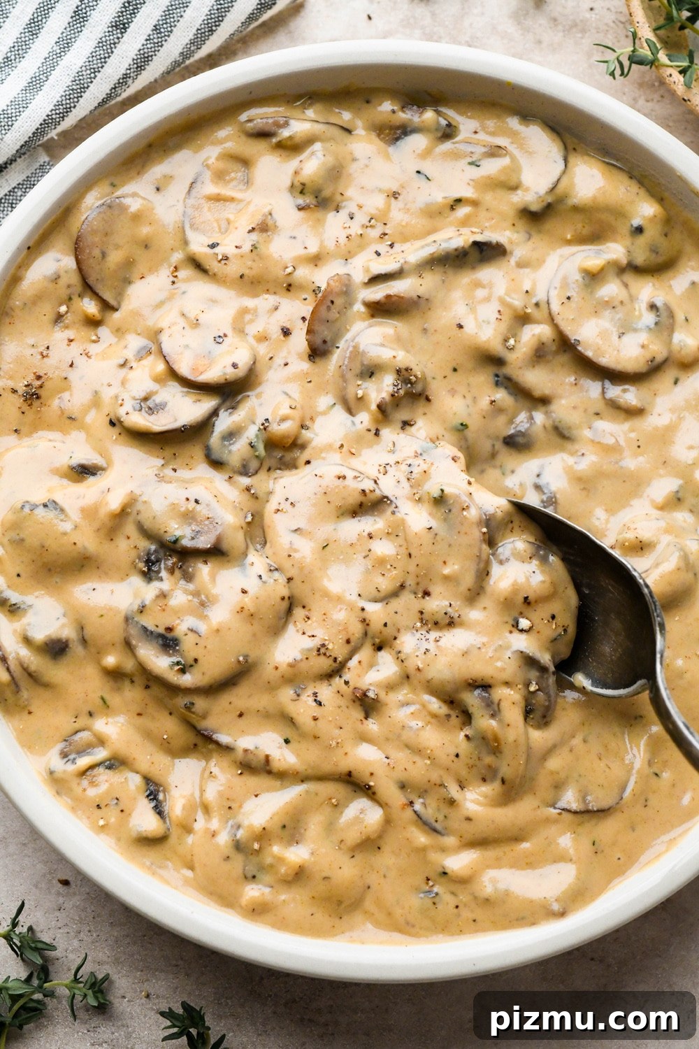 Creamy Gluten-Free Mushroom Gravy (Dairy-Free) 7 A bowl of thick and creamy gluten free mushroom gravy with a spoon dipping into the bowl to show the texture.