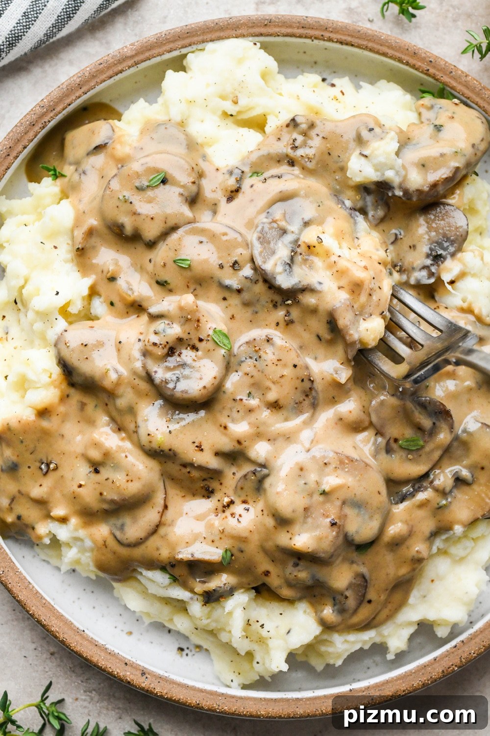 Creamy Gluten-Free Mushroom Gravy (Dairy-Free) 6 Close up image of a plate of mashed potatoes topped with mushroom gravy, with a fork digging into the creamy mashed potato and gravy combo.