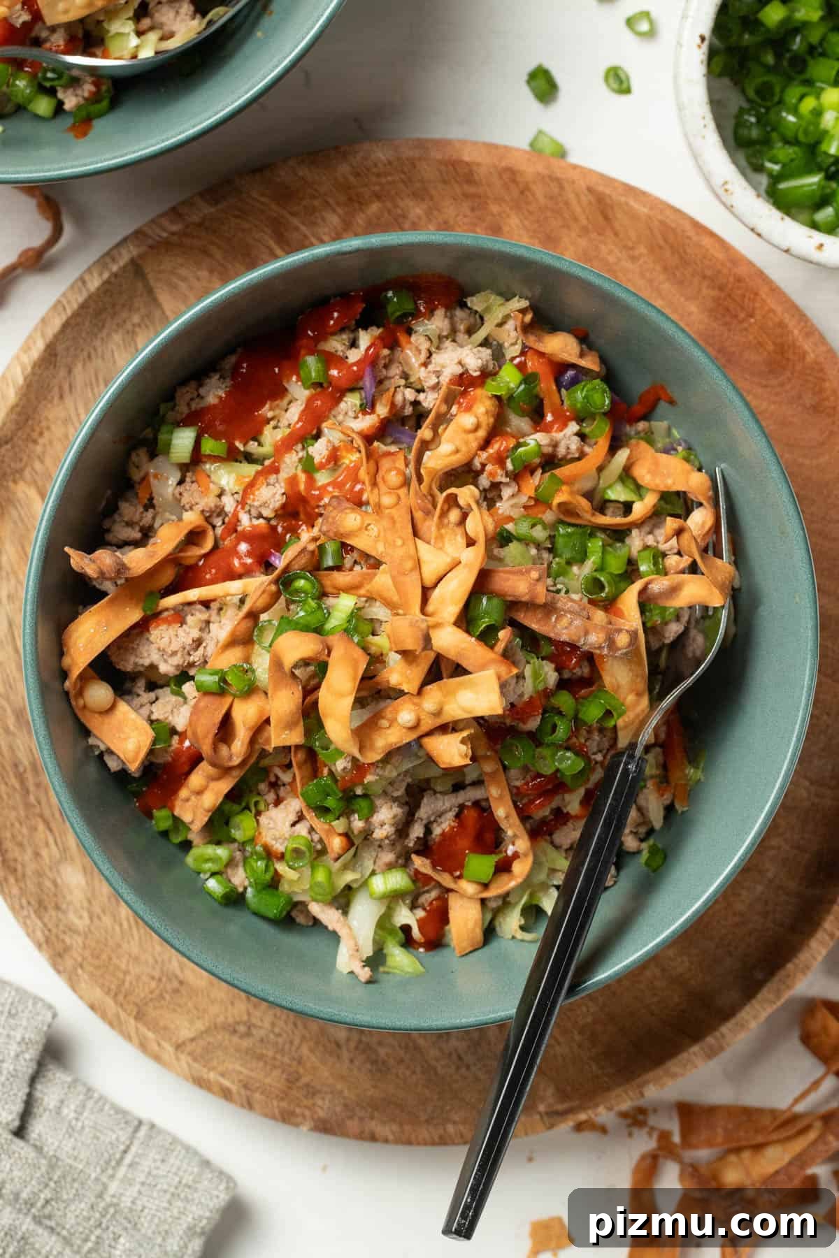 Ground Turkey Egg Roll Bowl with Soy-Ginger Sauce 2 Turkey egg roll bowls on a wood platter with a fork.